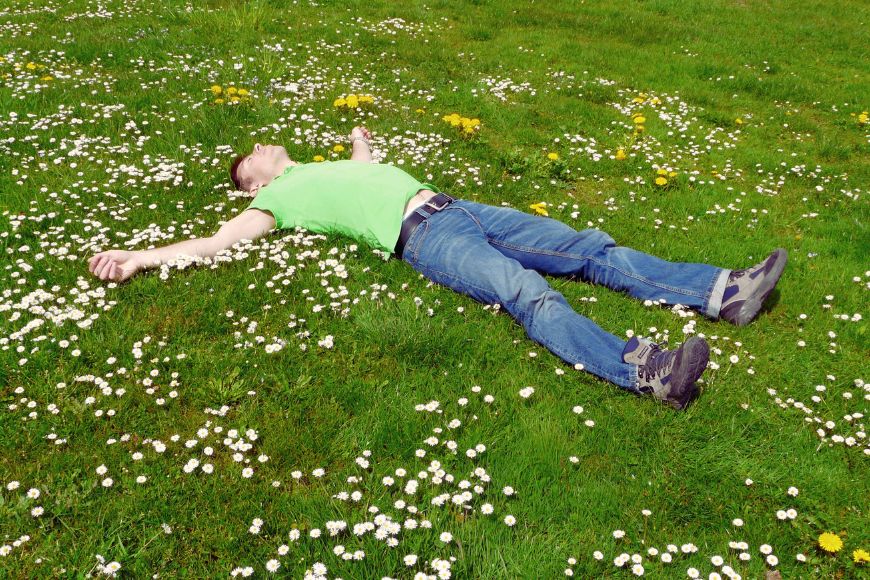 man-lying-on-grass-grounding